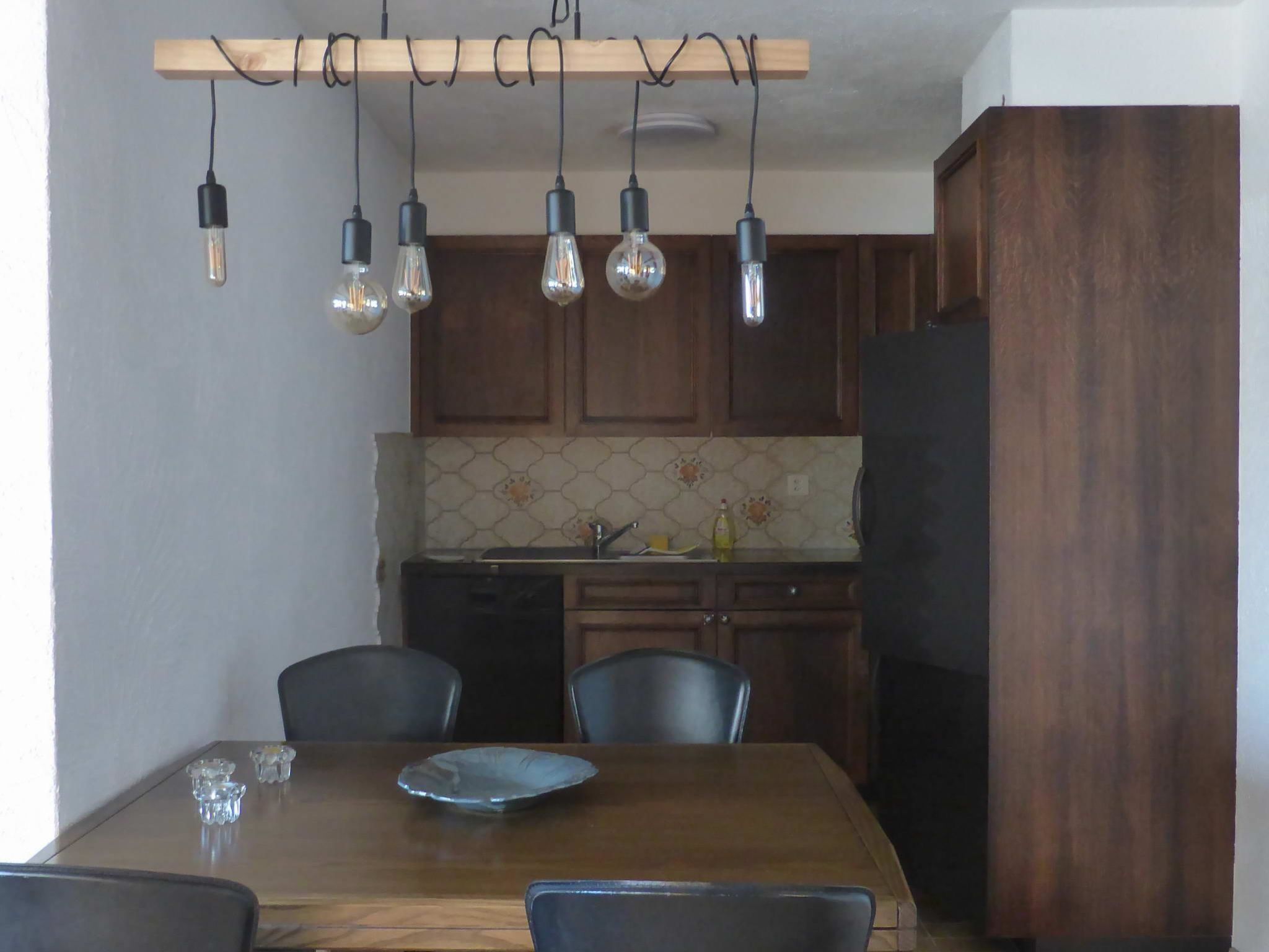 Un espace repas comprenant une table en bois, des chaises et des luminaires suspendus.