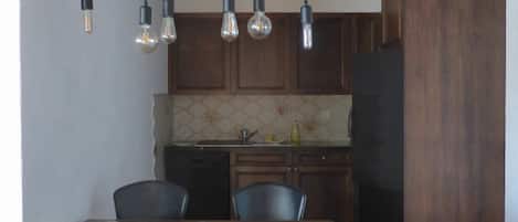 A dining area with a wooden table, chairs, and hanging light fixtures.