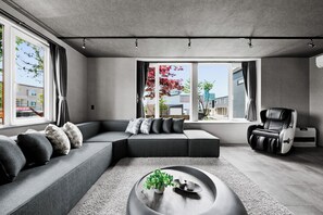 A modern living room with a sectional sofa, a massage chair, and a coffee table with a plant. - THE CROCUS ASAHIKAWA (Asahikawa)