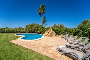 A swimming pool with a stone deck, surrounded by a grassy area and palm trees. - House with pool Son San Marti Gran Muro (Muro)