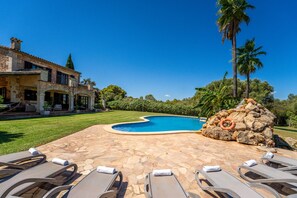 Piscina com espreguiçadeiras e um pátio de pedra.