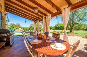 An outdoor patio with a wooden table set for dining, a grill, and a hammock. - House with pool Son San Marti Gran Muro (Muro)