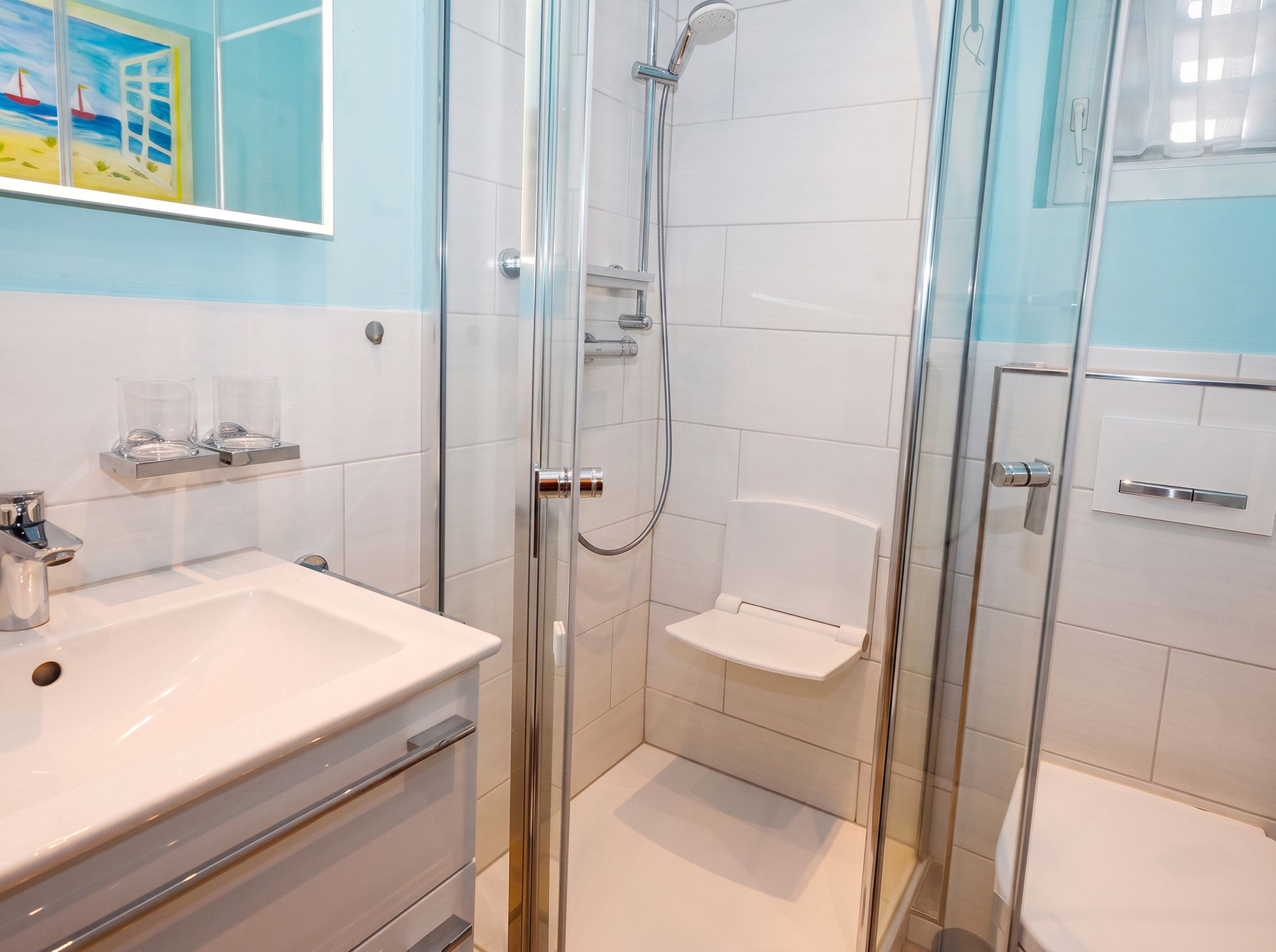 Ein modernes Badezimmer mit einer Duschkabine aus Glas, einem weißen Waschbecken und einem Spiegel.
