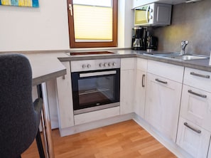 A compact kitchen with a built-in oven, a coffee maker, and a microwave. - Stunning Vacation Rental No. 32 at Haus Schloss am Meer in a Central Location (Büsum)