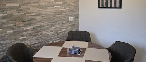 Un salón de conferencias con una mesa redonda, cuatro sillas, un proyector montado en la pared y una obra de arte enmarcada con el título 'AMORE'.