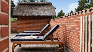 A brick wall with a thatched roof structure, a wooden bench with cushions, and a brick wall with a tiled roof. - VillaVilla 1005 - Vester Husby, Vestjylland (Ulfborg)