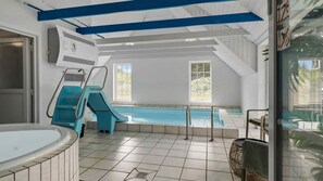 Ein Schwimmbeckenbereich mit Rutsche, Whirlpool und Fenster für natürliches Licht.