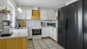 Eine moderne Küche mit weißen Schränken, einem schwarzen Kühlschrank und einer Mikrowelle.