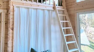 Une pièce avec un plafond en bois, un escalier, une fenêtre et un canapé.