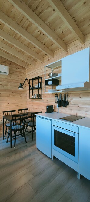 A kitchen with wooden walls, a white countertop, a stove, and a dining table with chairs.