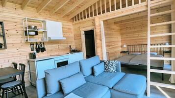A compact wooden cabin with a kitchenette, a sofa, and a bed.