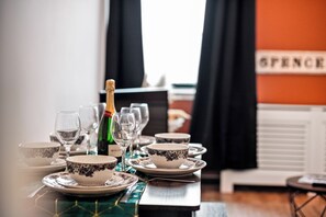 Mesa de jantar posta com tigelas brancas e azuis estampadas, copos de vinho e uma garrafa de champanhe.