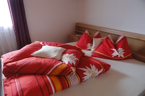 A hotel room with a bed, pillows, and a nightstand.