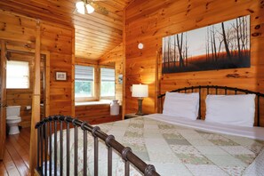 Een houten chaletinterieur met een bed, een schilderij, een raam en een deur.