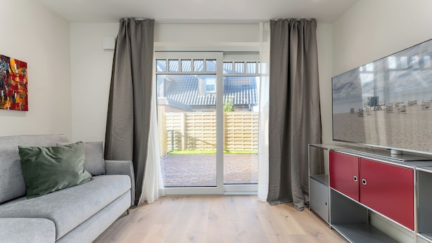 Una sala de estar moderna con un sofá gris, un televisor de pantalla plana y un mueble rojo.