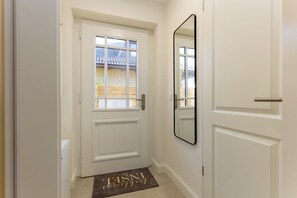 A white door with a window, a doormat with text, and a mirror on the wall. - Your modern North Sea getaway on Sylt for a relaxing vacation by the coast (Sylt)