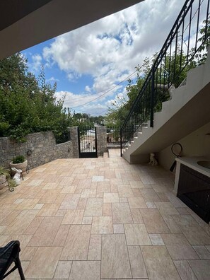 Eine großzügige Terrasse mit einer Steinmauer, einem Tor und einer Treppe, die zu einer oberen Ebene führt.