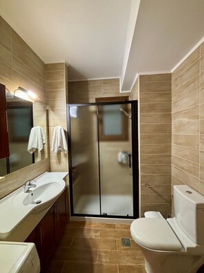 Ein modernes Badezimmer mit Duschkabine aus Glas, einem weißen Waschbecken und einer Toilette.