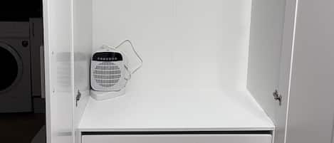 A white wardrobe with a hanging rack, a fan, and a built-in washing machine.