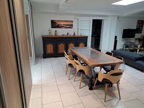 A dining area with a wooden table and chairs, a black cabinet with decorative items, and a television in the background. - Lovely apartment in a quiet neighborhood perfect for your stay (SECLIN)