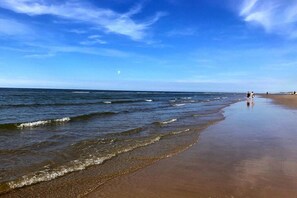 A beach with waves, a clear sky, and a few people walking. - Holiday home in Limmen with swimming pool (Limmen)
