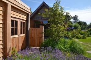 A wooden cabin with a fenced garden area and a variety of plants. - Holiday home in Limmen with swimming pool (Limmen)