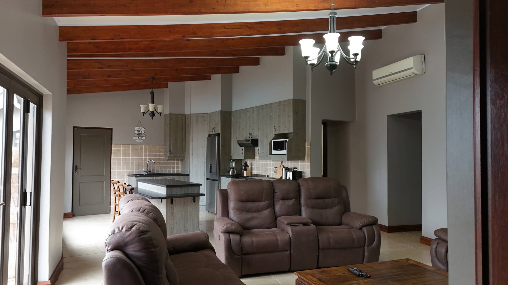 A modern living room with a brown leather sofa, a wooden coffee table, and a chandelier.