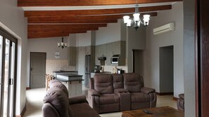 A modern living room with a brown leather sofa, a wooden coffee table, and a chandelier.