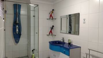 A modern bathroom with a glass-enclosed shower, a blue sink, and a mirror above the vanity.
