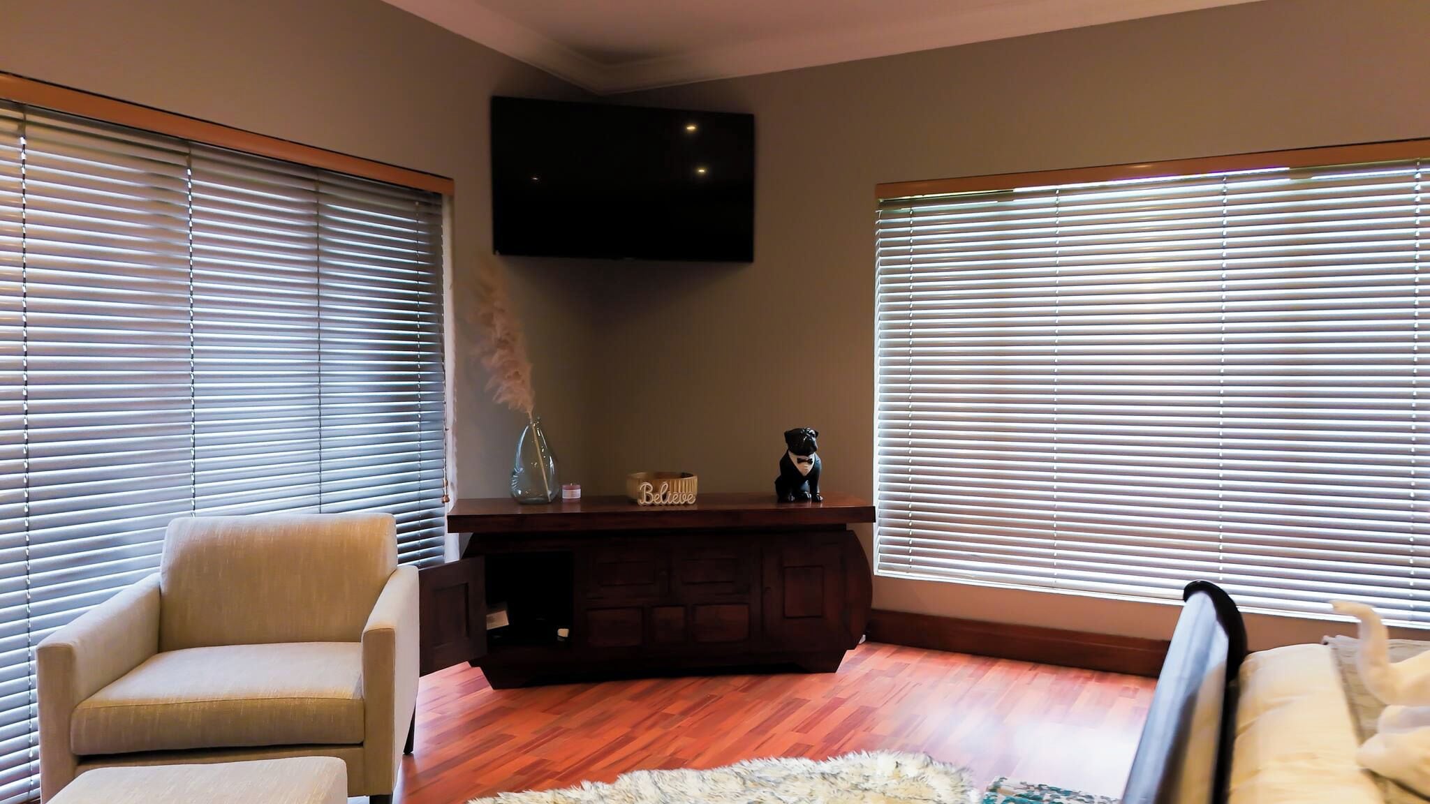 Una sala de estar con dos sofás, un televisor montado en la pared y un mueble de madera.