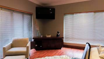 Una sala de estar con dos sofás, un televisor montado en la pared y un mueble de madera.