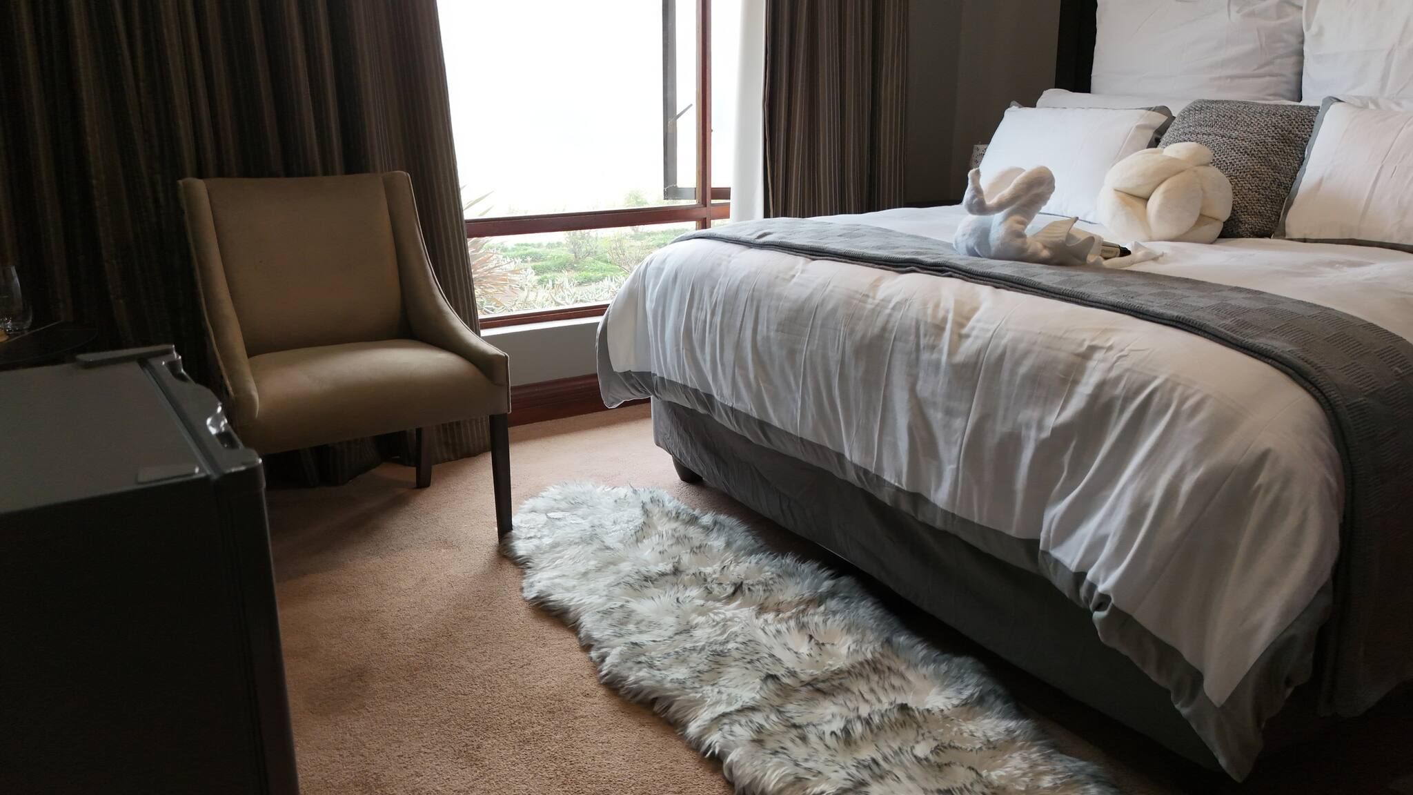 Une chambre à coucher avec un lit, une chaise, un tapis en fourrure et une fenêtre.