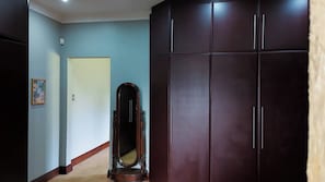 A hallway with a door, a mirror, and a wardrobe.