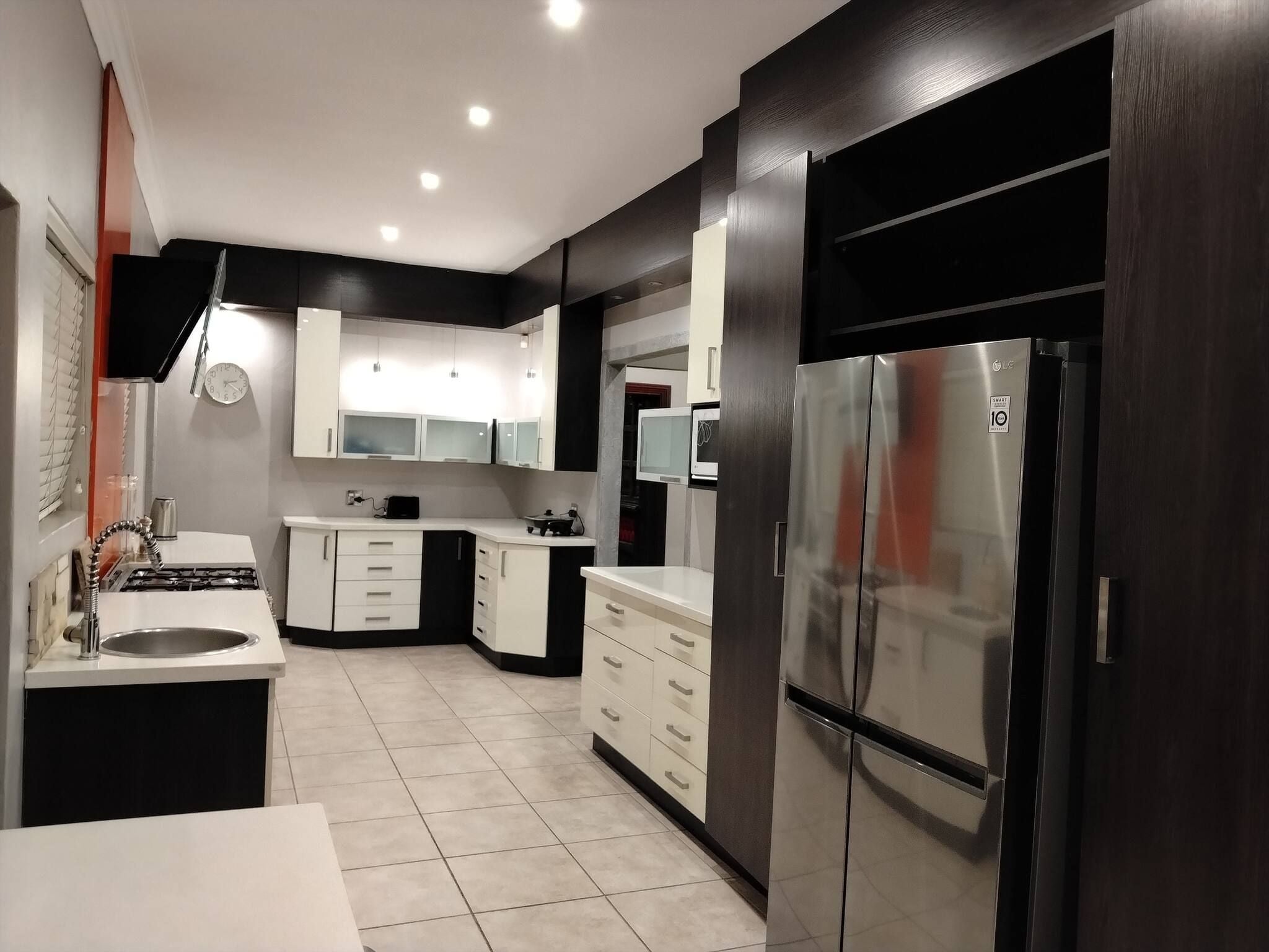 A modern kitchen with a stainless steel refrigerator, white cabinets, and a built-in microwave.