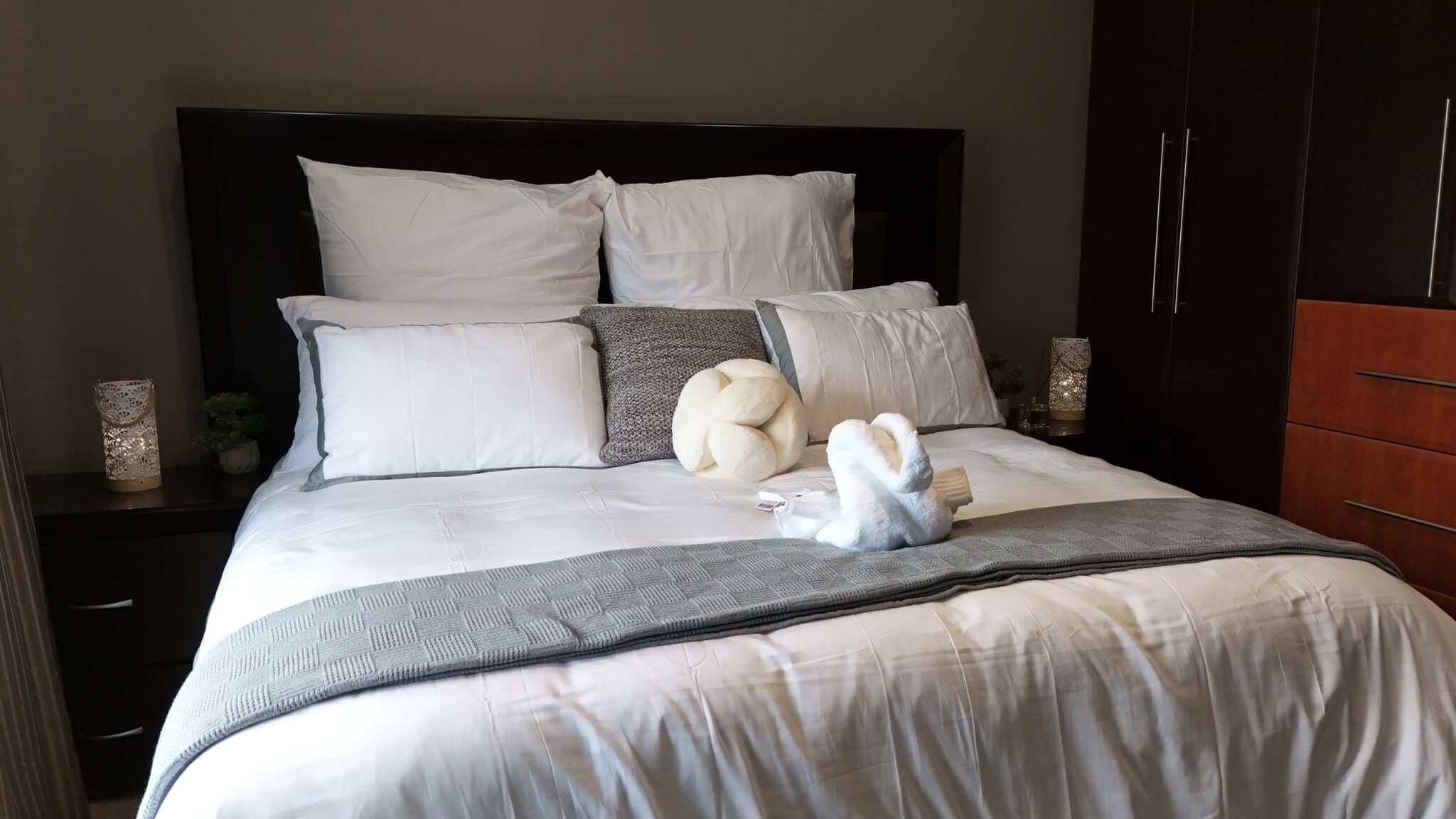 A neatly made bed with a white duvet, multiple pillows, and a decorative towel.