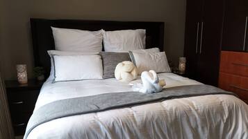 A neatly made bed with a white duvet, multiple pillows, and a decorative towel.