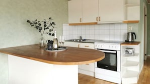 A compact kitchen with white cabinets, a wooden countertop, and a built-in oven.