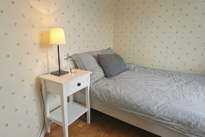 A bedroom with a bed, a bedside table with a lamp, and a wall with a pattern. - Seaside Guesthouse in Kalmar (Kalmar län)