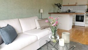 A modern living room with a sofa, a glass coffee table, and a vase with flowers.