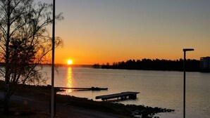 A sunset over a body of water with a dock and a bench.