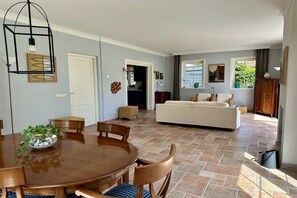Ein geräumiger Wohnbereich mit Esstisch, Sofa und Blick ins Freie.