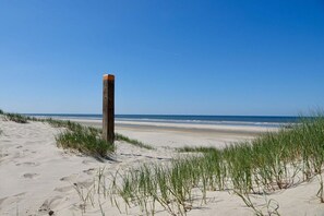 A sandy beach with a wooden post and grass in the foreground. - Holiday apartment with 3 bedrooms (Castricum)