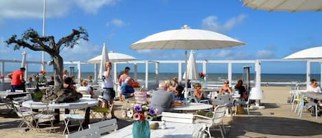 Un área de comedor al aire libre con mesas y sombrillas, con vista al mar.