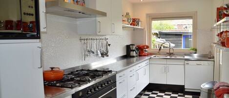 A kitchen with white cabinets, a black and white checkered floor, and a window with a view of a building outside.