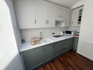 A modern kitchen with white cabinets, a stainless steel sink, and a microwave.