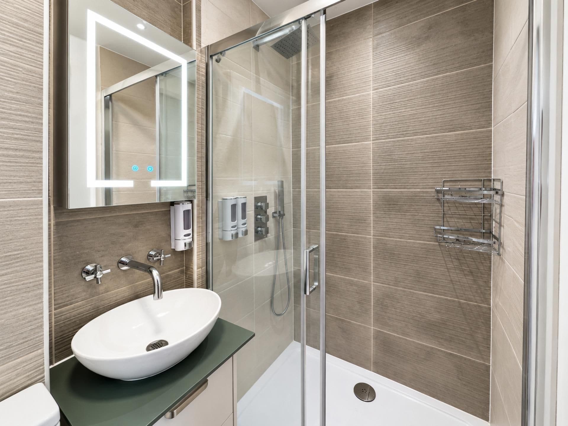 Een moderne badkamer met een douchecabine van glas, een wit wastafelmeubel en een spiegel met ingebouwde verlichting.