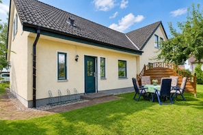 A two-story house with a tiled roof, a front door, and a small porch with outdoor furniture. - Enjoy a relaxing stay at the Dück vacation rental on Rügen (Putbus)