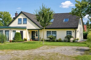 A two-story house with a sloped roof, a front porch, and a well-maintained lawn. - Enjoy a relaxing stay at the Dück vacation rental on Rügen (Putbus)