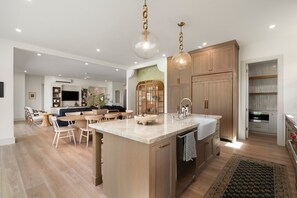 A modern kitchen with a central island, wooden cabinets, and pendant lighting. - Hale Olina by Alekona Kauai (Koloa)