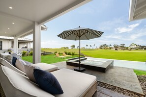 Ein überdachter Außenbereich mit einer Sitzecke, einem Sofa, einem Tisch und einem Sonnenschirm.